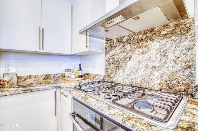 kitchen with stainless steel gas stovetop, white cabinetry, light stone counters, and wall chimney exhaust hood