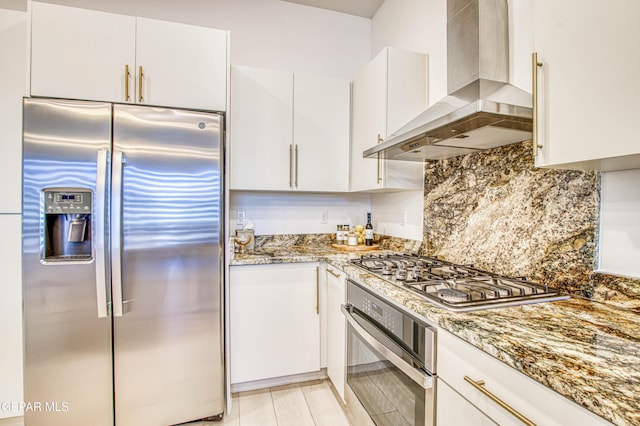 kitchen featuring stone counters, appliances with stainless steel finishes, white cabinets, and range hood