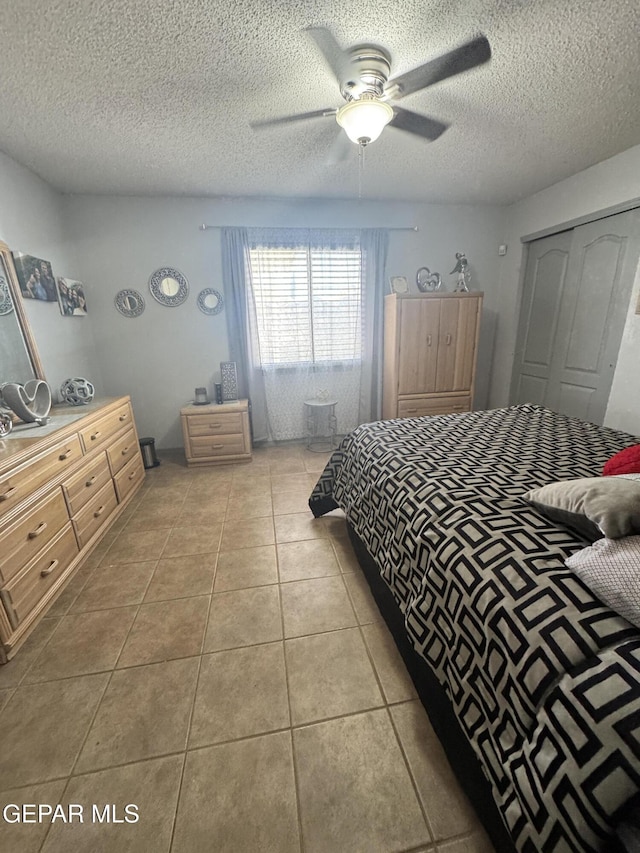 bedroom featuring light tile patterned floors, a textured ceiling, and ceiling fan