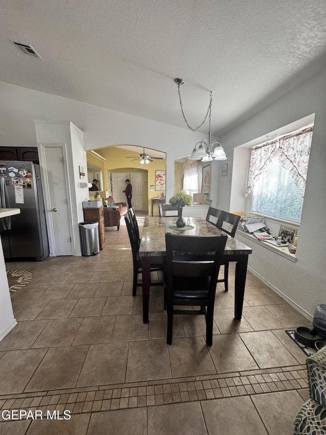 dining area featuring ceiling fan with notable chandelier, tile patterned floors, and a textured ceiling