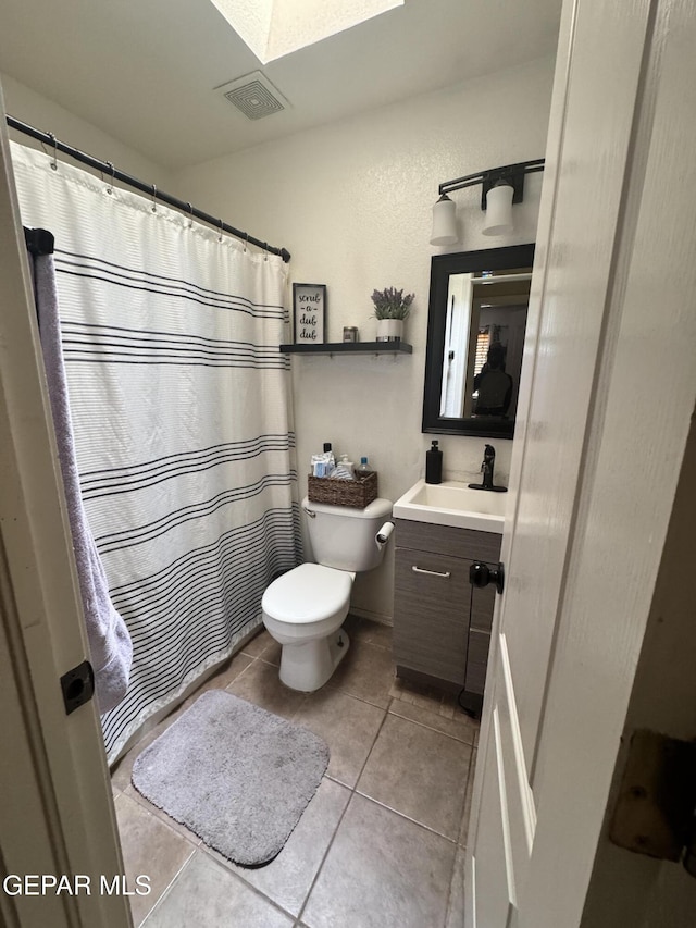 bathroom featuring a skylight, vanity, tile patterned floors, and toilet