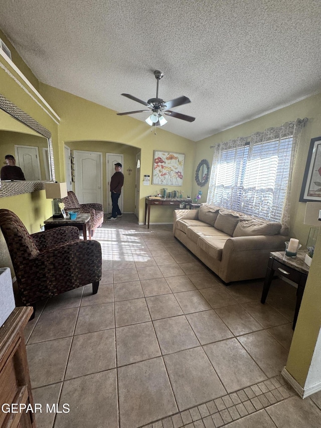 tiled living room with ceiling fan, lofted ceiling, and a textured ceiling