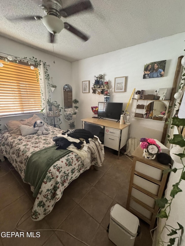 bedroom with ceiling fan, a textured ceiling, and dark tile patterned floors