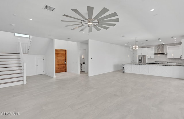 unfurnished living room featuring ceiling fan with notable chandelier