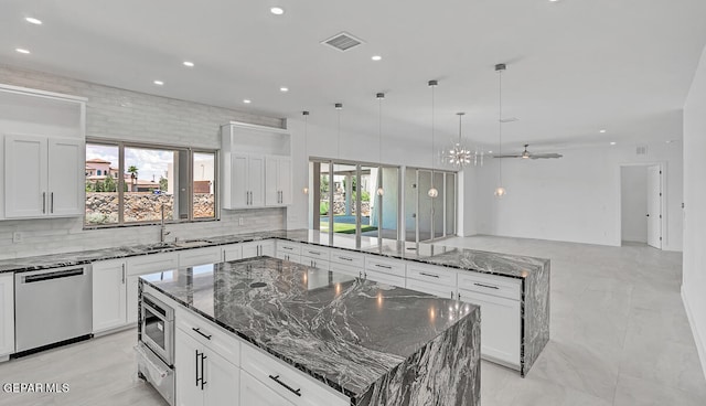 kitchen featuring white cabinets, appliances with stainless steel finishes, a large island, and dark stone countertops