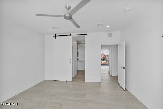 unfurnished room featuring a barn door and ceiling fan