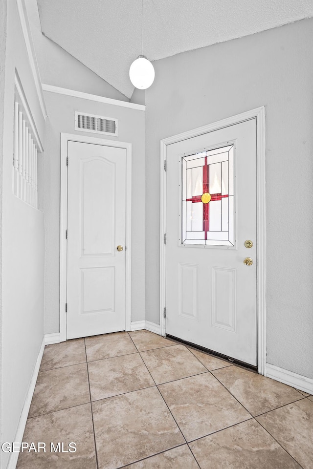 entrance foyer with lofted ceiling, light tile patterned floors, and a textured ceiling