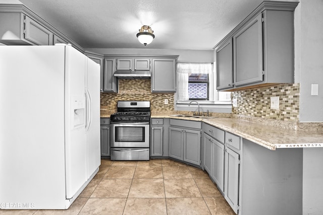 kitchen featuring gray cabinets, sink, white refrigerator with ice dispenser, light tile patterned floors, and stainless steel range with gas stovetop