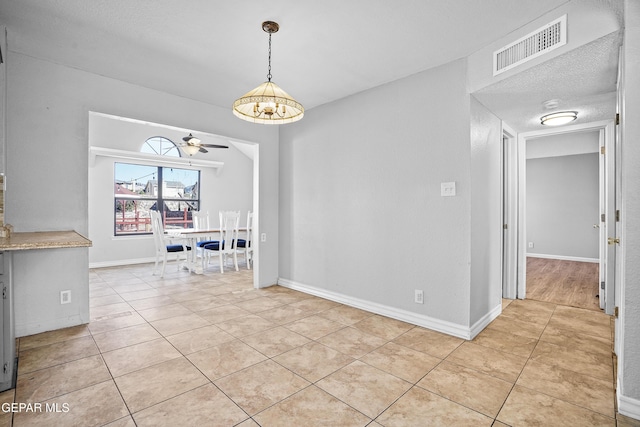 unfurnished dining area featuring light tile patterned floors, a textured ceiling, and ceiling fan