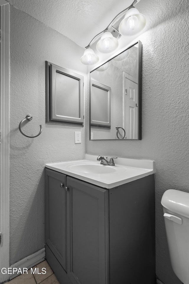 bathroom with vanity, toilet, and a textured ceiling