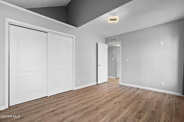 unfurnished bedroom with a closet, hardwood / wood-style floors, and a textured ceiling