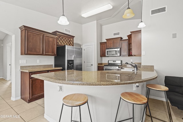 kitchen featuring pendant lighting, stainless steel appliances, kitchen peninsula, and sink