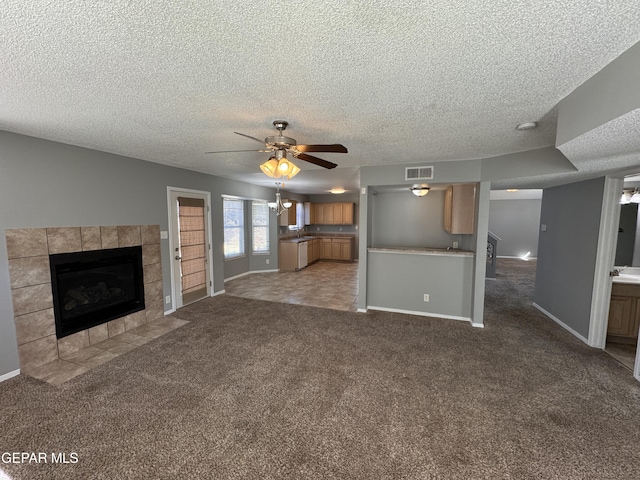 unfurnished living room featuring a textured ceiling, a fireplace, light colored carpet, and ceiling fan