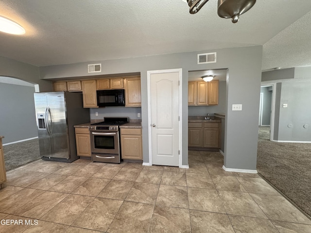 kitchen with stainless steel appliances, light colored carpet, and a textured ceiling