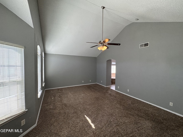 empty room with dark colored carpet, high vaulted ceiling, a textured ceiling, and ceiling fan