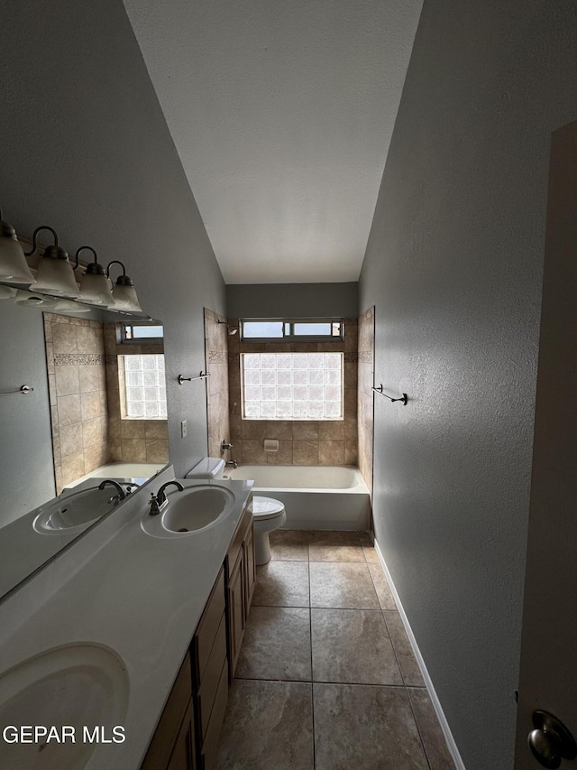 bathroom featuring vanity, lofted ceiling, tile patterned floors, and toilet