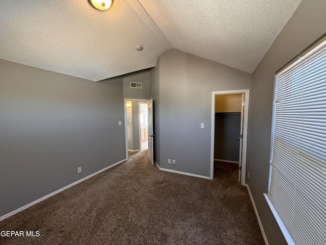 unfurnished bedroom featuring dark carpet, vaulted ceiling, and a textured ceiling