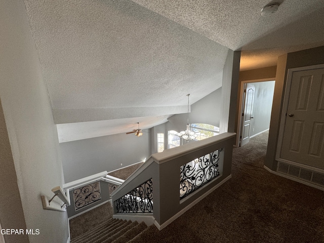 hall featuring a notable chandelier, vaulted ceiling, a textured ceiling, and dark carpet