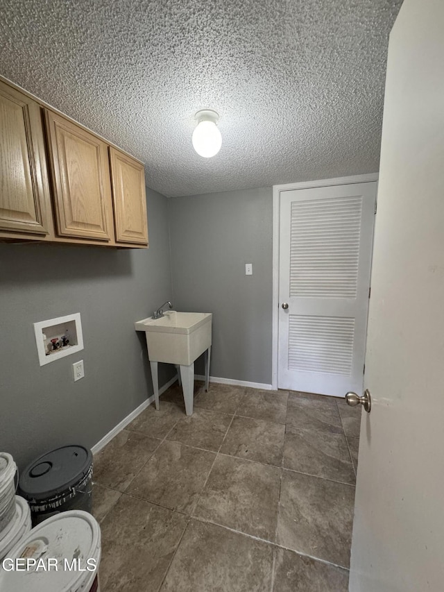 laundry room featuring hookup for a washing machine, cabinets, and a textured ceiling