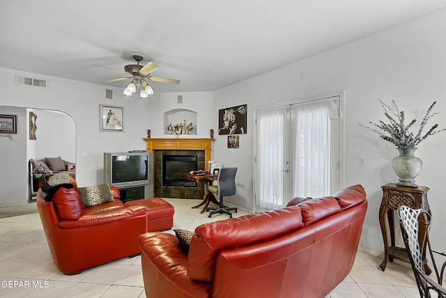 tiled living room featuring ceiling fan, a fireplace, and french doors