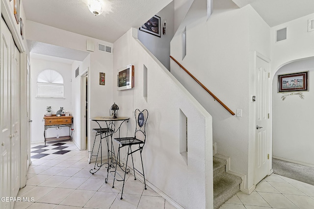 stairs with tile patterned floors and a textured ceiling