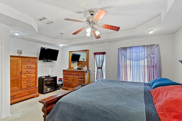 carpeted bedroom featuring a raised ceiling and ceiling fan