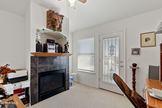 living room featuring a tile fireplace, ceiling fan, and carpet flooring