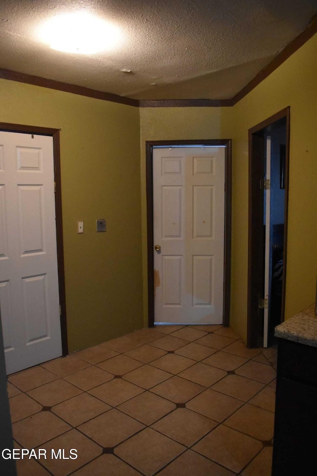 interior space featuring crown molding, tile patterned floors, and a textured ceiling