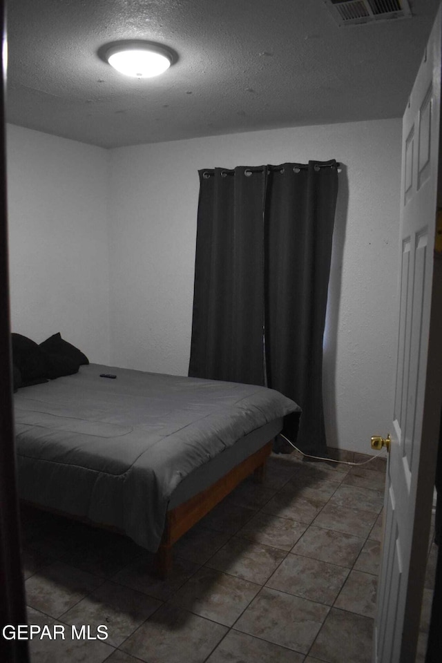 bedroom with tile patterned floors and a textured ceiling