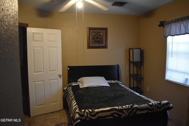 tiled bedroom featuring ceiling fan