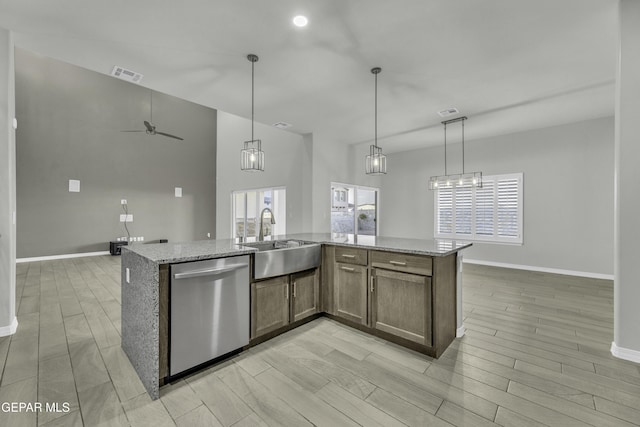 kitchen featuring sink, hanging light fixtures, light stone counters, an island with sink, and stainless steel dishwasher