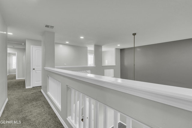 hallway with dark colored carpet