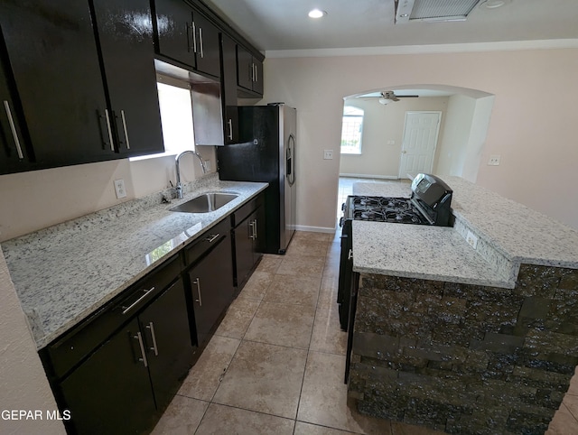 kitchen featuring light stone counters, sink, gas stove, and light tile patterned flooring