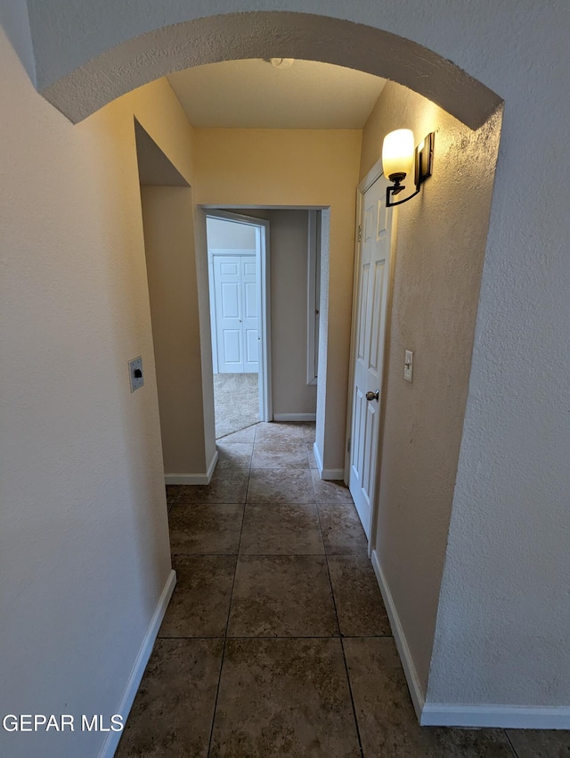 hallway featuring dark tile patterned floors