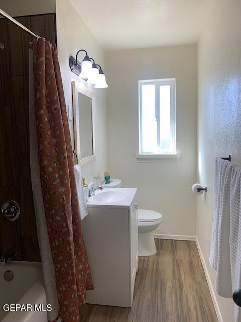 full bathroom featuring shower / bath combo with shower curtain, wood-type flooring, toilet, and vanity