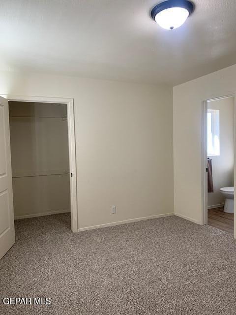 unfurnished bedroom with carpet floors, connected bathroom, and a closet