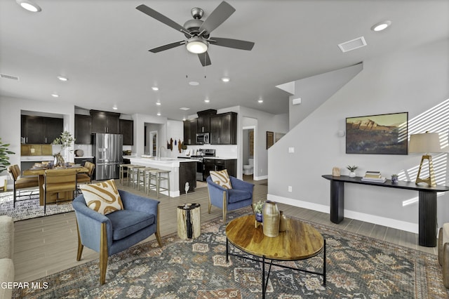 living room with ceiling fan, sink, and dark hardwood / wood-style flooring