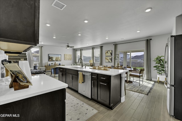 kitchen featuring appliances with stainless steel finishes, a kitchen island with sink, sink, and ceiling fan