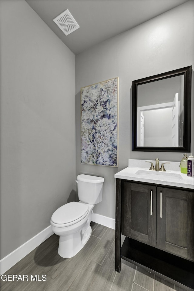 bathroom featuring wood-type flooring, toilet, and vanity