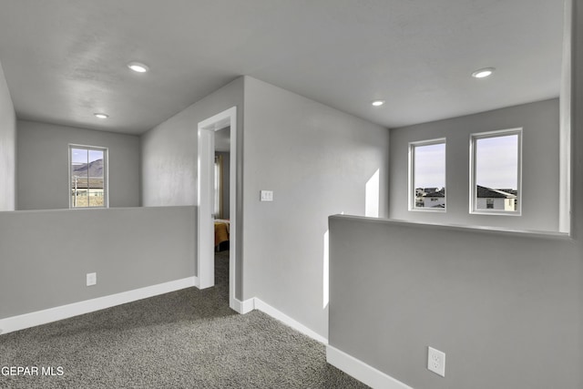 hall with dark colored carpet