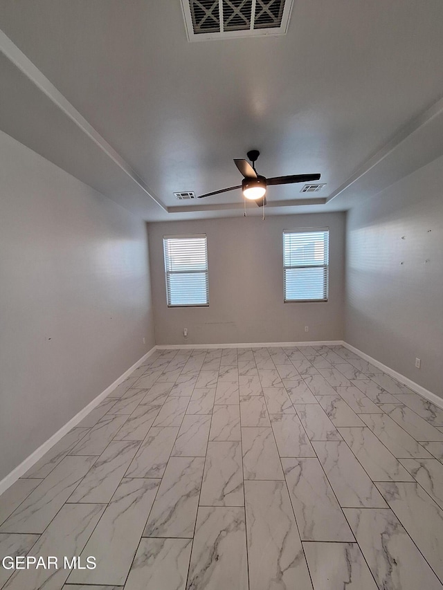 empty room with a healthy amount of sunlight, ceiling fan, and a tray ceiling