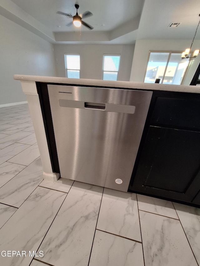 kitchen featuring a raised ceiling, ceiling fan with notable chandelier, and stainless steel dishwasher