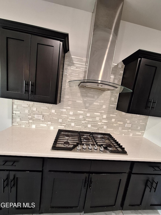 kitchen with stainless steel gas cooktop, wall chimney range hood, and backsplash