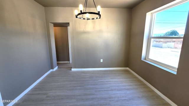 unfurnished dining area with wood-type flooring and a notable chandelier