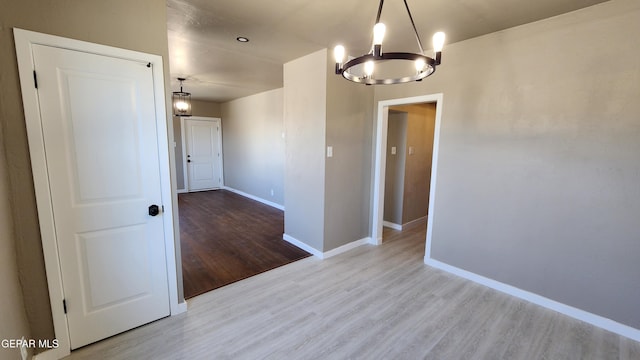 spare room with a notable chandelier and light hardwood / wood-style floors