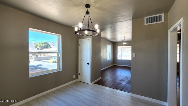 unfurnished dining area with hardwood / wood-style floors and an inviting chandelier