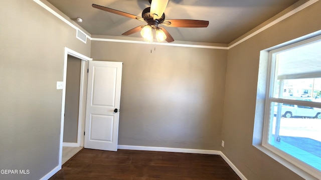 spare room with ornamental molding, plenty of natural light, dark wood-type flooring, and ceiling fan