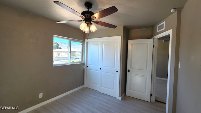 unfurnished bedroom featuring light hardwood / wood-style floors, a closet, and ceiling fan