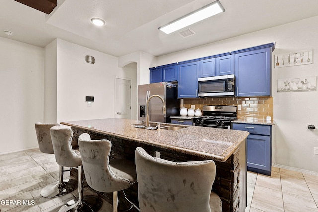 kitchen with sink, a breakfast bar area, appliances with stainless steel finishes, a kitchen island with sink, and backsplash