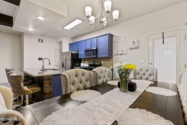 dining area with sink, hardwood / wood-style floors, and a notable chandelier